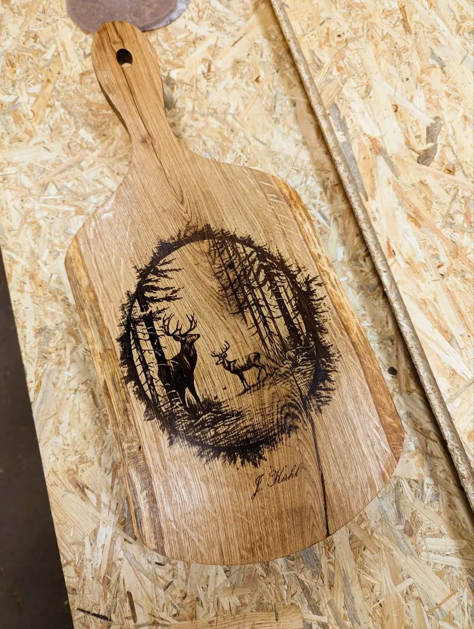 Ein Holzschneidebrett mit einer Gravur von Hirschen im Wald