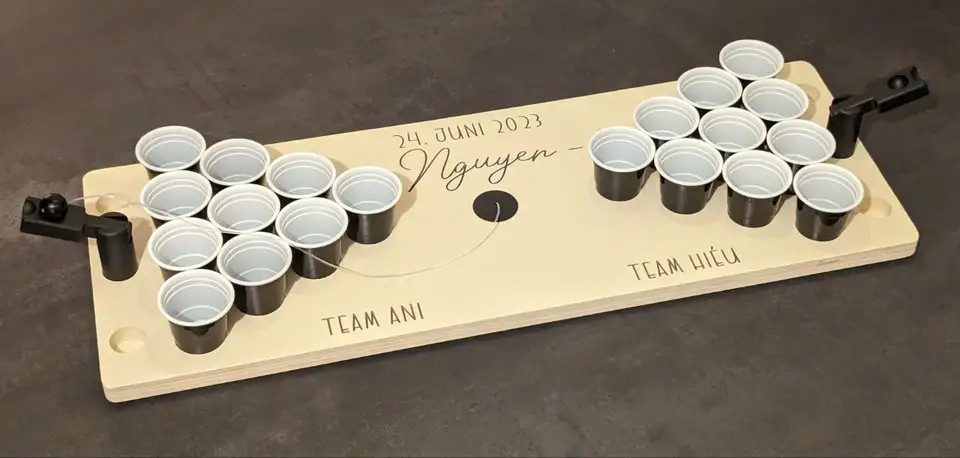Ein personalisiertes Miniatur-Beerpong-Brett aus Holz mit schwarzen Bechern